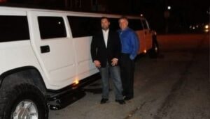 Two men by white Hummer limo